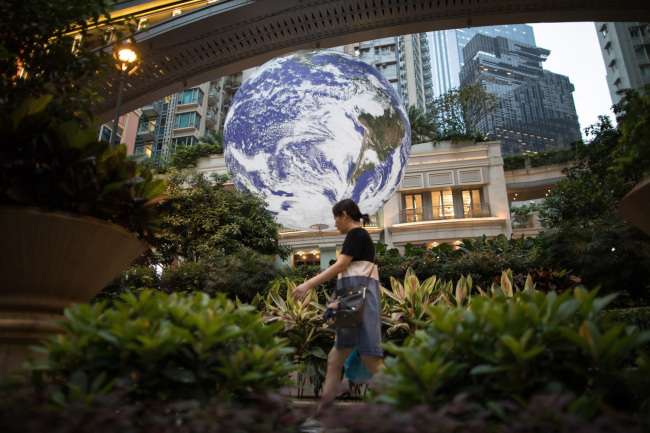 A woman walks past British artist Luke Jerram's giant earth installation in Hong Kong, China, May 2, 2019. [Photo: IC]