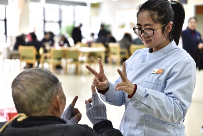 A staff member plays games with an aged person at an elderly care center in Hefei, Anhui Province on March 4, 2019. [File photo: VCG]