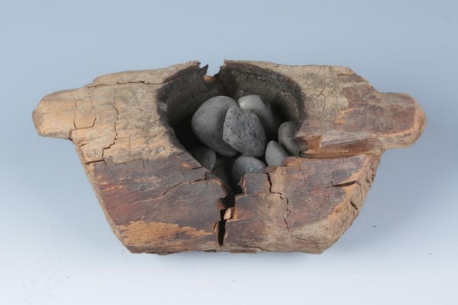 In this photo received by AFP on June 11, 2019 from the Institute of Archaeology, Chinese Academy of Social Sciences, a wooden brazier (burner) and stones used to burn cannabis that was excavated from the Jirzankal cemetery, located northeast of Qushiman Village in the Tashkurgan Tajik Autonomous County of Xinjiang province, is displayed. At a burial site high in the Pamir Mountains, music from an ancient harp and the smell of burning cannabis and juniper incense fill the air, part of an elaborate ceremony to commune with the divine -- or the deceased. These rituals took place 2,500 years ago and represent the oldest known use of marijuana for its psychoactive properties, according to scientists who analyzed archeological remains at the Jirzankal Cemetery in China’s western Xinjiang province using forensic technology. Their findings were published in the journal Science Advances on Wednesday and place cannabis among the growing number of crops researchers believe evolved along the Silk Road, said Robert Spengler, one of the study’s authors and its lead archaeobotanist. [Photo: <br/>Xinhua Wu / Institute of Archaeology, Chinese Academy of Social Sciences / AFP]