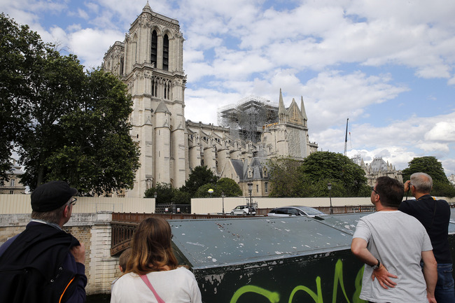 People look at the Notre Dame cathedral during the first mass celebrate after the massive fire which ravaged the roof of the famous monument two months ago on June 15, 2019, in Paris, France. [Photo: VCG]