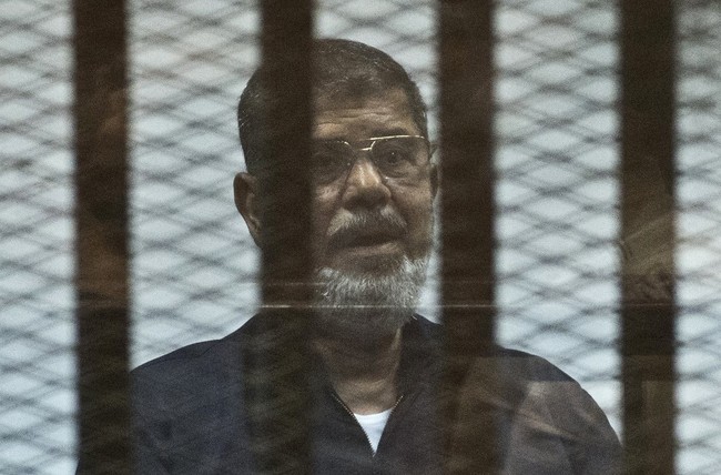 In this file photo taken on June 16, 2015 Egypt's ousted Islamist president Mohamed Morsi stands behind the bars during his trial in Cairo. [Photo: AFP]