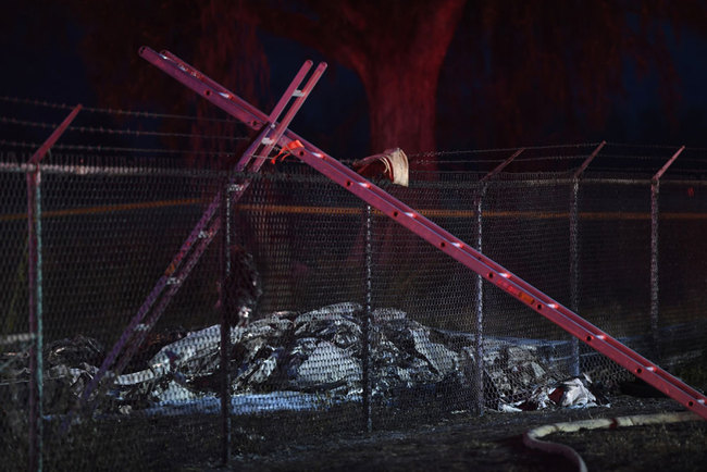 Remnants of an aircraft carrying nine people lies on the ground near a fence that surrounds Dillingham Airfield in Mokuleia, just off Farrington Highway, Friday, June 21, 2019. Nine people on board the twin engine aircraft died Friday night in a crash on Oahu's North Shore, officials said. [Photo: Honolulu Star-Advertiser via AP/Bruce Asato]