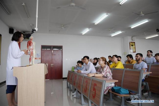 Teacher Li Na (L) gives a lecture on acupuncture for students at home and abroad in Shaanxi University of Chinese Medicine in northwest China's Shaanxi Province. [Photo: Xinhua] 