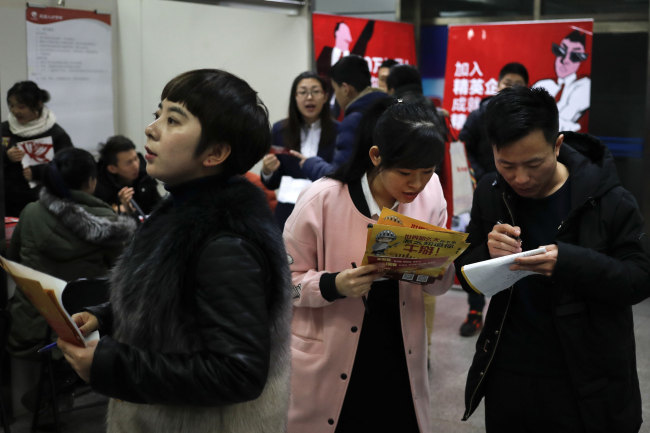 Job seekers look for vacancy information at a job fair at the Beijing's Talented Market in Beijing, Wednesday, Feb. 8, 2017. [Photo: IC]