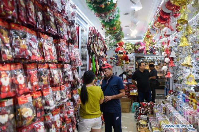 A foreign businessman selects(挑选 tiāoxuǎn) Christmas commodities at the Yiwu International Trade City in Yiwu, China's small commodity hub in east China's Zhejiang Province, June 26, 2019.[Photo: Xinhua] 