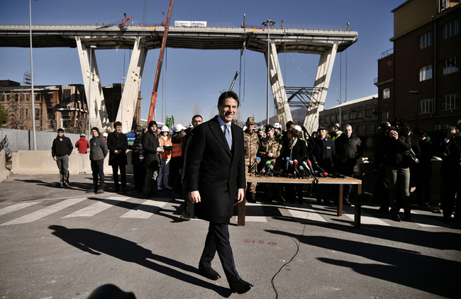 Italy’s Prime Minister Giuseppe Conte (C) walks by during a visit to the demolition site of the western section of the remains of the Morandi Bridge in Genoa on February 8, 2019, to launch the official start of demolition of the first meters of the bridge's western section. [Photo: AFP/Marco Bertorello]