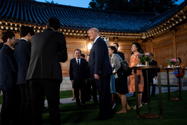 South Korea's President Moon Jae-in (C, background) and US President Donald Trump (3rd) meet members of K-pop band EXO (L) before attending a working dinner at the tea house on the grounds of the presidential Blue House in Seoul on June 29, 2019. [Photo: AFP]
