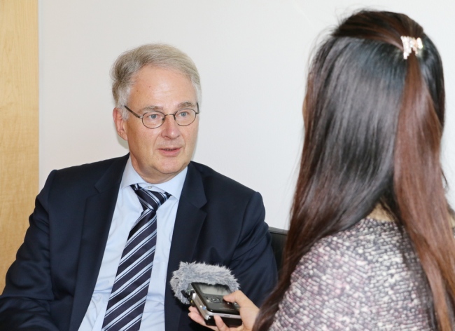 The file photo shows Dr. Roland Hartwig, a member of the foreign-affairs committee of Germany's legislative assembly speaking with a reporter.[Photo:China Plus]