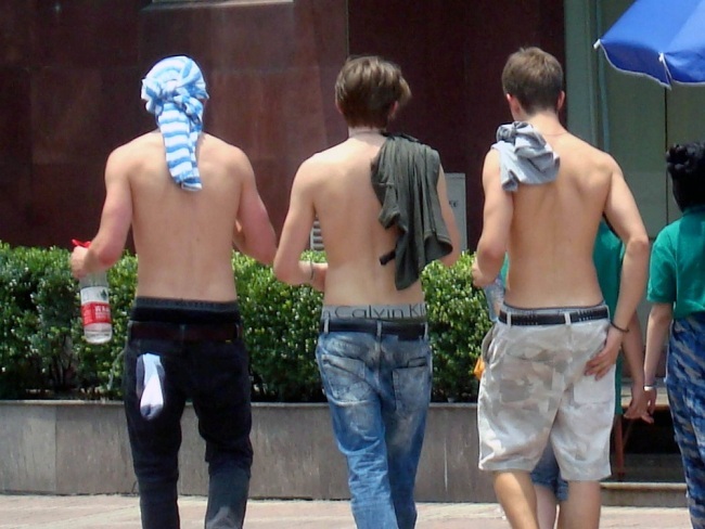 Shirtless pedestrians walking along a street in Suzhou, Jiangsu Province, on June 19, 2010. [File photo: IC]