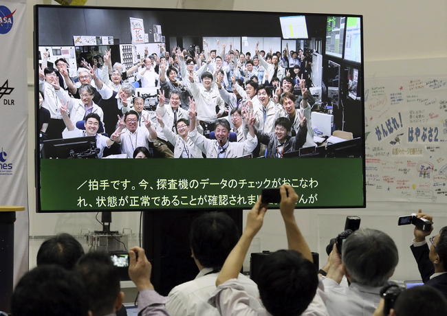 A monitor shows people pose for camera at the control room at the press center in Japan Aerospace Exploration Agency (JAXA) Sagamihara Campus in Sagamihara City, Kanagawa Prefecture on July 11, 2019. [Photo: IC]