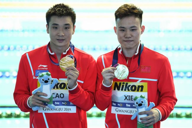 Gold medallist China's Cao Yuan and China's Xie Siyi celebrate during the medals ceremony of the men's synchronised 3m springboard diving event during the 2019 World Championships at Nambu International Aquatics Centre in Gwangju on July 13, 2019. [Photo: VCG/AFP/Manan Vatsyayana]