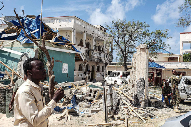 A man passes in front of the rubbles of the popular Medina hotel of Kismayo on July 13, 2019, a day after at least 26 people, including several foreigners, were killed and 56 injured in a suicide bomb and gun attack claimed by Al-Shabaab militants. [Photo: VCG]