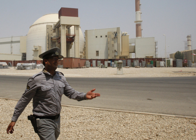 An Iranian security official directs media at the Bushehr nuclear power plant, with the reactor building seen in the background, just outside the southern city of Bushehr, Iran. [File photo: IC] 