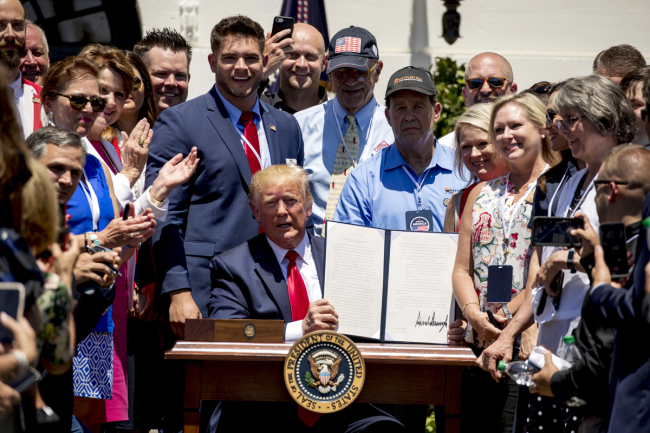Company representatives invited to the White House stand next to President Donald Trump as he holds up an executive order after he signs it during a Made in America showcase on the South Lawn in Washington, July 15, 2019. [Photo: AP via IC/Andrew Harnik]