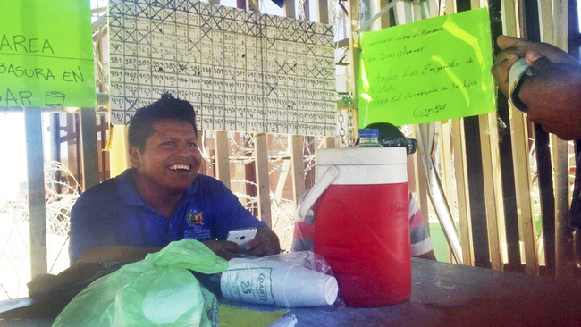 In this July 2, 2019 photo provided by Jesse Telleria, asylum seeker Claudio Aviles sits by a posted list of migrants who are in San Luis Río Colorado, Mexico, waiting to seek asylum in the United States. [Photo: AP/Jesse Telleria]