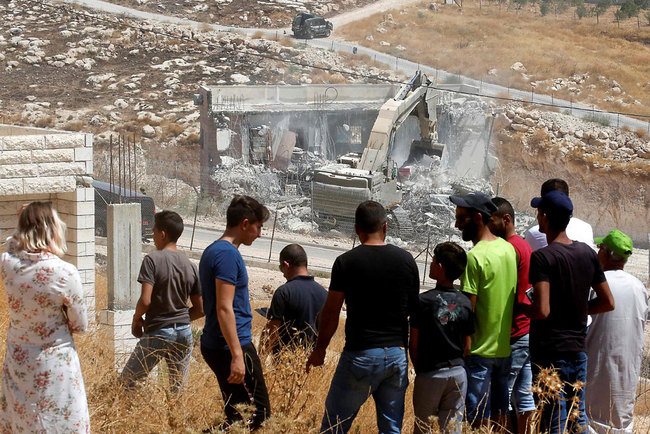 This picture taken from the West Bank on July 22, 2019 shows Palestinians looking at Israeli security forces tearing down one of the Palestinian buildings still under construction which have been issued notices to be demolished in the Wadi al-Hummus area adjacent to the Palestinian village of Sur Baher in East Jerusalem. [Photo: VCG/Hazem Bader]