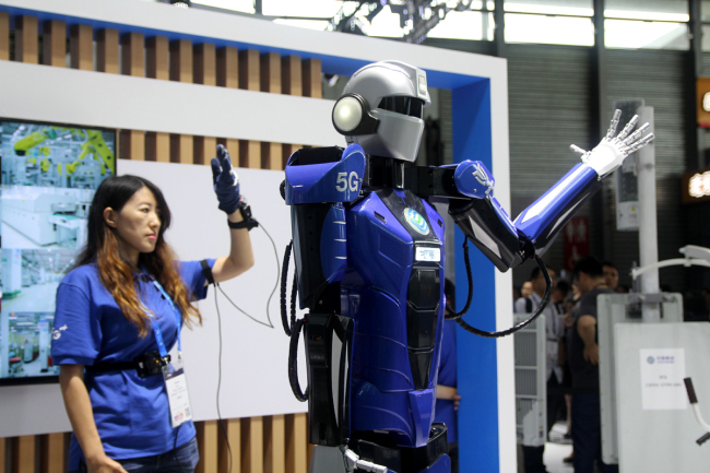 A visitor interacts with a 5G robot during the 2019 Mobile World Congress in Shanghai on June 26, 2019. [Photo: IC]
