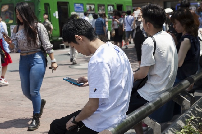 People using their smartphones in Tokyo's Shibuya District on July 27, 2016. [File Photo: IC/Rodrigo Reyes Marin]