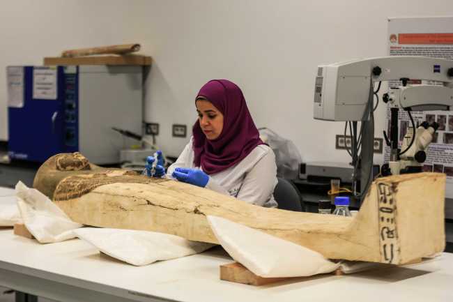 An Egyptian archaeologist works on a sarcophagus which belonged to King Tutankhamun during a restoration process at the restoration lab of the newly-built Grand Egyptian Museum in Giza outside Cairo, August 4, 2019. [Photo: dpa via IC/Mohamed Hossam]