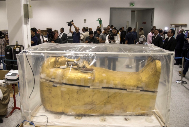 Reporters stand around the gilded coffin of King Tutankhamun that is undergoing a restoration process at the Grand Egyptian Museum in Giza, Egypt, 04 August 2019. [Photo: EPA via IC/Mohamed Hossam]