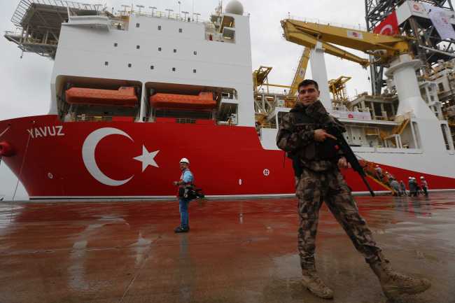 In this Thursday, June 20, 2019 file photo, a Turkish police officer patrols the dock, backdropped by the drilling ship 'Yavuz' to be dispatched to the Mediterranean, at the port of Dilovasi, outside Istanbul. [File Photo: AP via IC/Lefteris Pit arakis]