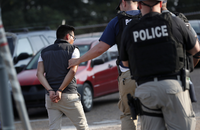 A man is taken into custody at a Koch Foods Inc. plant in Morton, Miss., on Wednesday, Aug. 7, 2019. [Photo: IC/ AP Photo/Rogelio V. Solis]