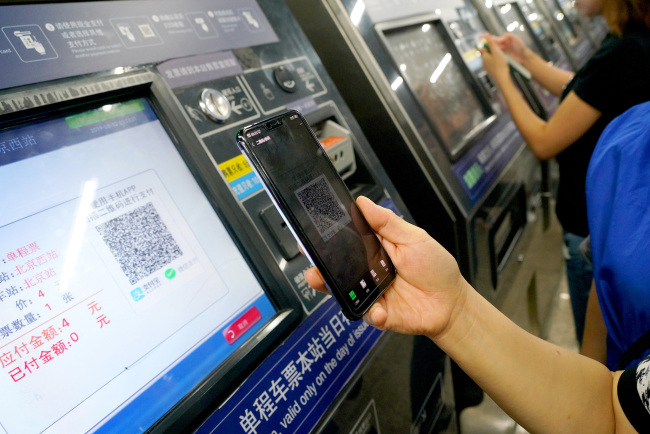 A passenger buys a ticket by scanning a QR code on a ticket machine at a subway station in Beijing on August 10, 2019. [Photo: VCG]