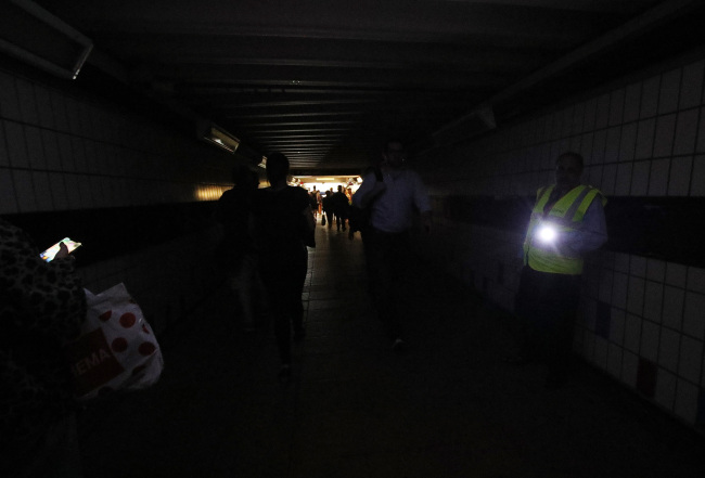 People walking in complete darkness at Clapham Junction station in London during a power cut, which has caused apocalyptic rush-hour scenes across England and Wales, with traffic lights down and trains coming to a standstill. [Photo: PA via VCG/PA Images]