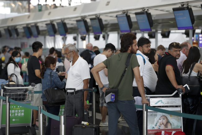 Travelers wait to check in for their flights at the Airport in Hong Kong, Wednesday, Aug. 14, 2019. [Photo: AP/Vincent Thian]
