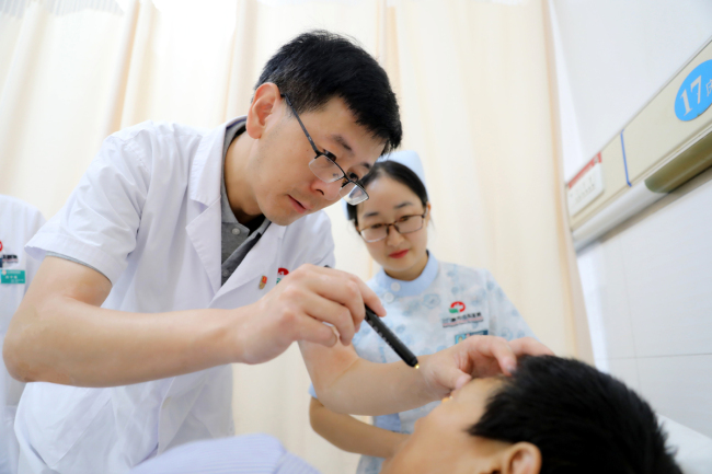 A doctor checks on patients at Sanmenxia Central Hospital, in Sanmenxia City, Henan Province, on August 19, 2019. [Photo: IC]
