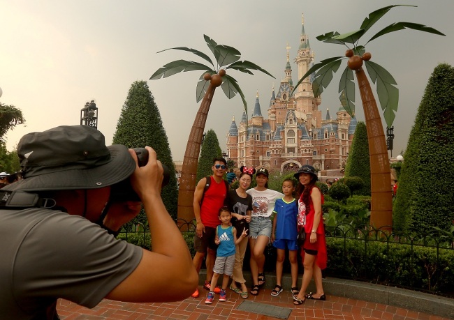 Tourists take group photo in front of the Disney castle in Shanghai Disneyland Resort. [File Photo: UPI via IC/Stephen Shaver]