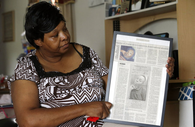 In this photo taken Tuesday, Aug. 6, 2019 Brenda Scurlock is shown in her home in Lumber Bridge, N.C. holding a newspaper clipping about her son's murder. [File photo: AP]