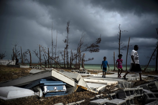 People walk next to a shattered and water-filled coffin lays exposed to the elements in the aftermath of Hurricane Dorian, at the cemetery in Mclean's Town, Grand Bahama, Bahamas, Friday Sept. 13, 2019. [Photo: AP]