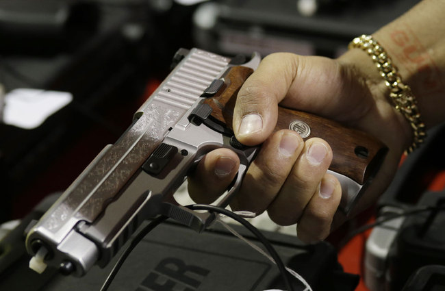 In this Jan. 9, 2016, file photo, a customer looks at a SIG Sauer hand gun at a gun show held by Florida Gun Shows in Miami. [File photo: AP via IC/Lynne Sladky]