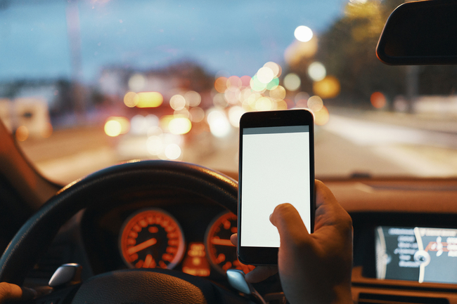 File photo of someone driving while checking phone message [Photo: VCG]