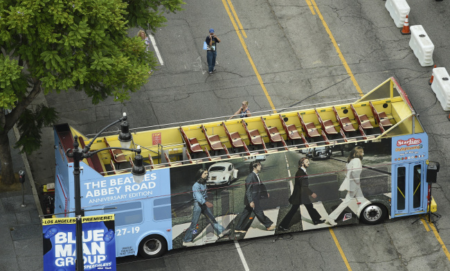 Fans take pictures in front of a double-decker bus decorated with the cover of the classic 1969 Beatles album "Abbey Road" after an event to celebrate its 50th anniversary in front of the Capitol Records building, Thursday, Sept. 26, 2019, in Los Angeles. [Photo: AP/Chris Pizzello]