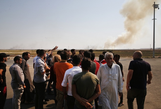 People watch from Akcakale, Sanliurfa Province, southeastern Turkey, as smoke billows from fires on targets in Tel Abyad, Syria, caused by bombardment by Turkish forces, Sunday, Oct. 13, 2019. [Photo: IC]