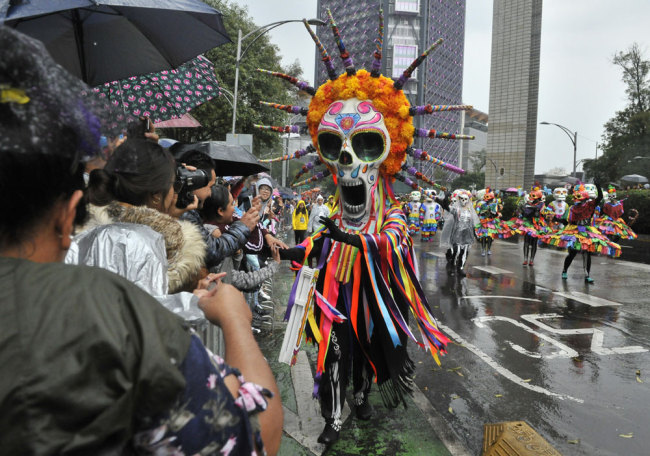 People take part in the Day of the Dead parade along Reforma avenue in Mexico City, on October 27, 2019. [Photo: AFP/Claudio Cruz]