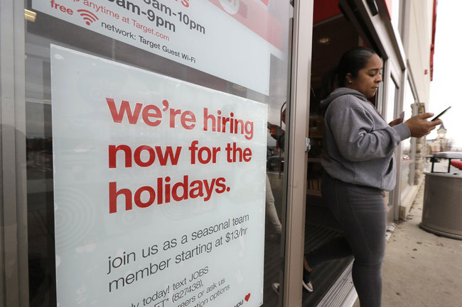 In this Nov. 27, 2019 photo a passer-by walks past a hiring for the holidays sign near an entrance to a Target store location, in Westwood, Mass. [Photo: AP]