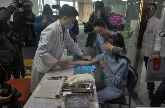 A doctor from a Shenyang-based plastic surgery hospital prepares to collect blood from Xiao Feng on Saturday, December 7, 2019. [Photo: VCG]