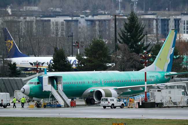 Workers walk near a Boeing 737 Max airplane being built for Oman Air at Renton Municipal Airport in Renton, Wash, on Monday, Dec. 16. [File photo: AP/Ted S. Warren]