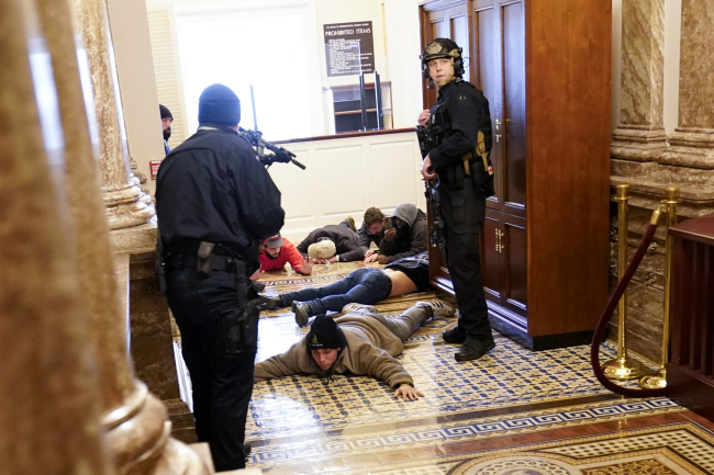 Americká kapitolská policie zadržuje demonstranty uvnitř amerického Kapitolu ve Washingtonu DC dne 6. ledna 2021. Fotografie: AP