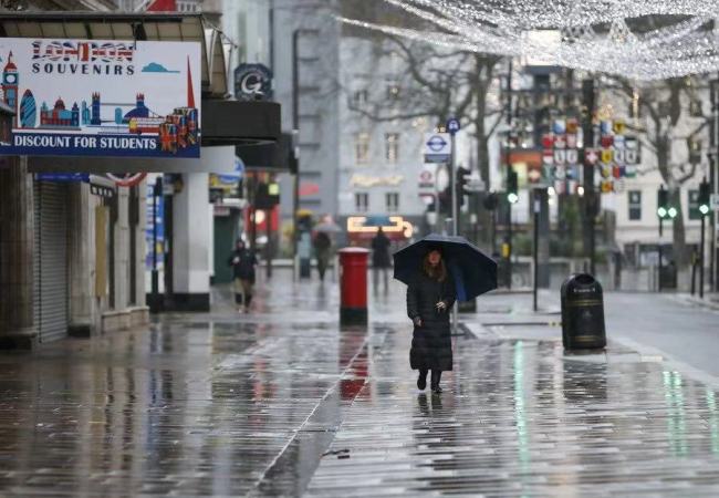Žena kráčí 21. prosince 2020 na prázdné ulici poblíž náměstí Leicester v Londýně ve Velké Británii. (Xinhua / Han Yan)