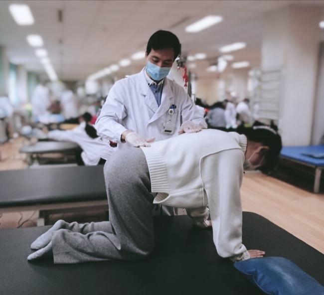 Guo Jingwei instruuje pacienta, aby cvičil jako součást fyzické aktivity, dne 14. ledna 2020. [Fotografie: Li Hongrui / chinadaily.com.cn]