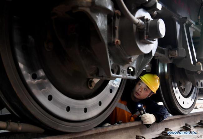 Zaměstnanec společnosti China Railway Zhengzhou Bureau Group Co., Ltd. kontroluje kola vlaku v Zhengzhou (Čeng-čou) v provincii Henan (Che-nan) ve střední Číně, 11. února 2021. Lidé z různých odvětví zastávají své funkce v předvečer čínského lunárního Nového roku, neboli Jarního svátku, který připadá na 12. února. (Xinhua / Li An)