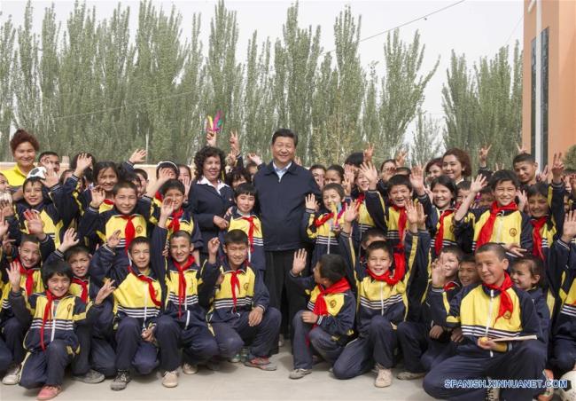 Xi Jinping posa para una fotografía grupal con alumnos y maestros de la escuela primaria central en el municipio de Tokkuzak, distrito de Shufu, en la región autónoma uygur de Xinjiang, en el noroeste de China, el 28 de abril de 2014. (Xinhua/Xie Huanchi)