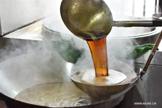  Un ouvrier manie le sucre brun récemment fabriqué dans un atlier à Zunyi, dans la province du Guizhou (sud-ouest), le 6 janvier. Les producteurs locaux sont très occupés à fabriquer du sucre brun pour répondre à la demande du marché à l'approche de la Fête du printemps. (Photo : Luo Xinghan)