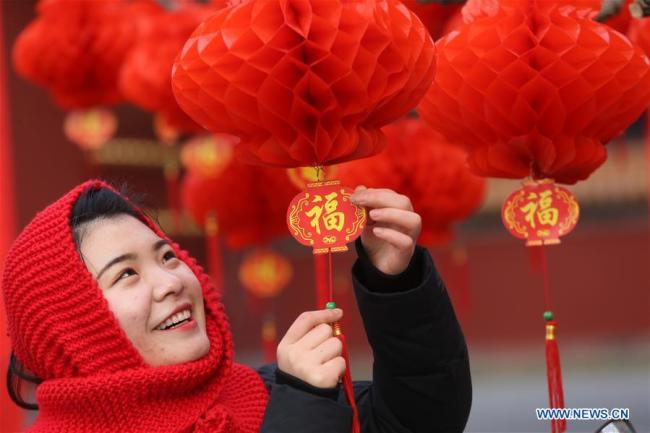 Une jeune fille regarde des lanternes à la porte sud du parc Ditan, également connu sous le nom de parc du Temple de la Terre, le 27 janvier 2018 à Beijing. (Photo / Xinhua)