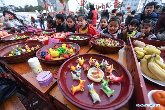 Des enfants regardent des gâteaux de riz colorés dans le village de Hexidai du bourg de Tangqi, à Hangzhou, capitale de la province du Zhejiang (est de la Chine), le 1er février 2018. Des habitants locaux ont participé jeudi à une série d'activités traditionnelles pour accueillir le Nouvel An lunaire chinois qui tombe cette année le 16 février. (Xinhua/Xu Yu)