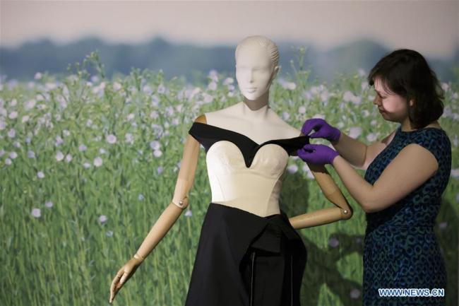 Une membre du personnel travaille sur une robe exposée lors de l'exposition intitulée "Fashioned from Nature" au Victoria and Albert Museum à Londres, au Royaume-Uni, le 18 avril 2018. L'exposition ouvrira ses portes au public le 21 avril, explorant la relation entre la mode et la nature. (Xinhua/Tim Ireland)